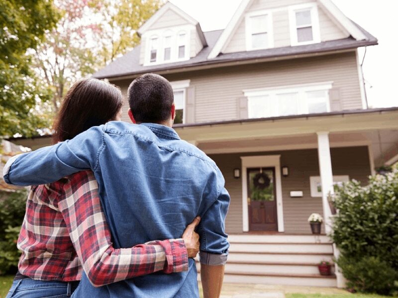 Mature Couple Standing in Front of Their Mansion